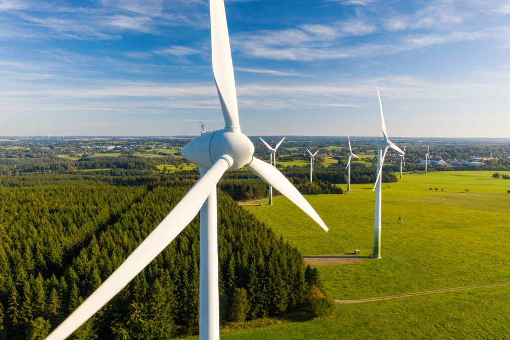 Photo of wind turbines against a blue sky and green fields.